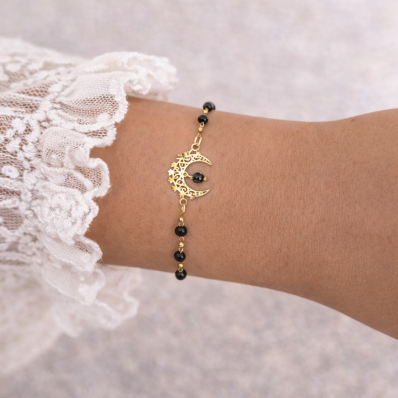 Delikatna bransoletka na złotym łańcuszku z ażurowym półksiężycem i fasetowanymi czarnymi koralikami z naturalnego turmalinu. Subtelny, elegancki dodatek idealny do codziennych i kobiecych stylizacji.