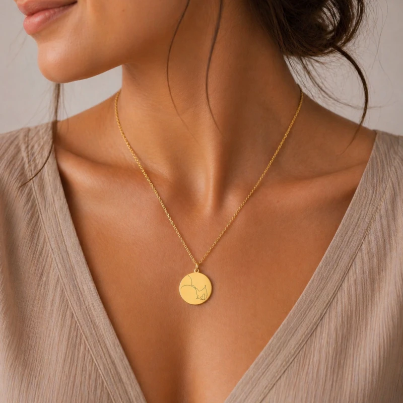 Złoty naszyjnik dla mamy z delikatną grafiką mama i dziecko prezentowany na modelce. Subtelna biżuteria podkreślająca kobiecy styl i emocjonalny charakter produktu.